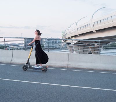 A photo of a woman riding an E-scooter.